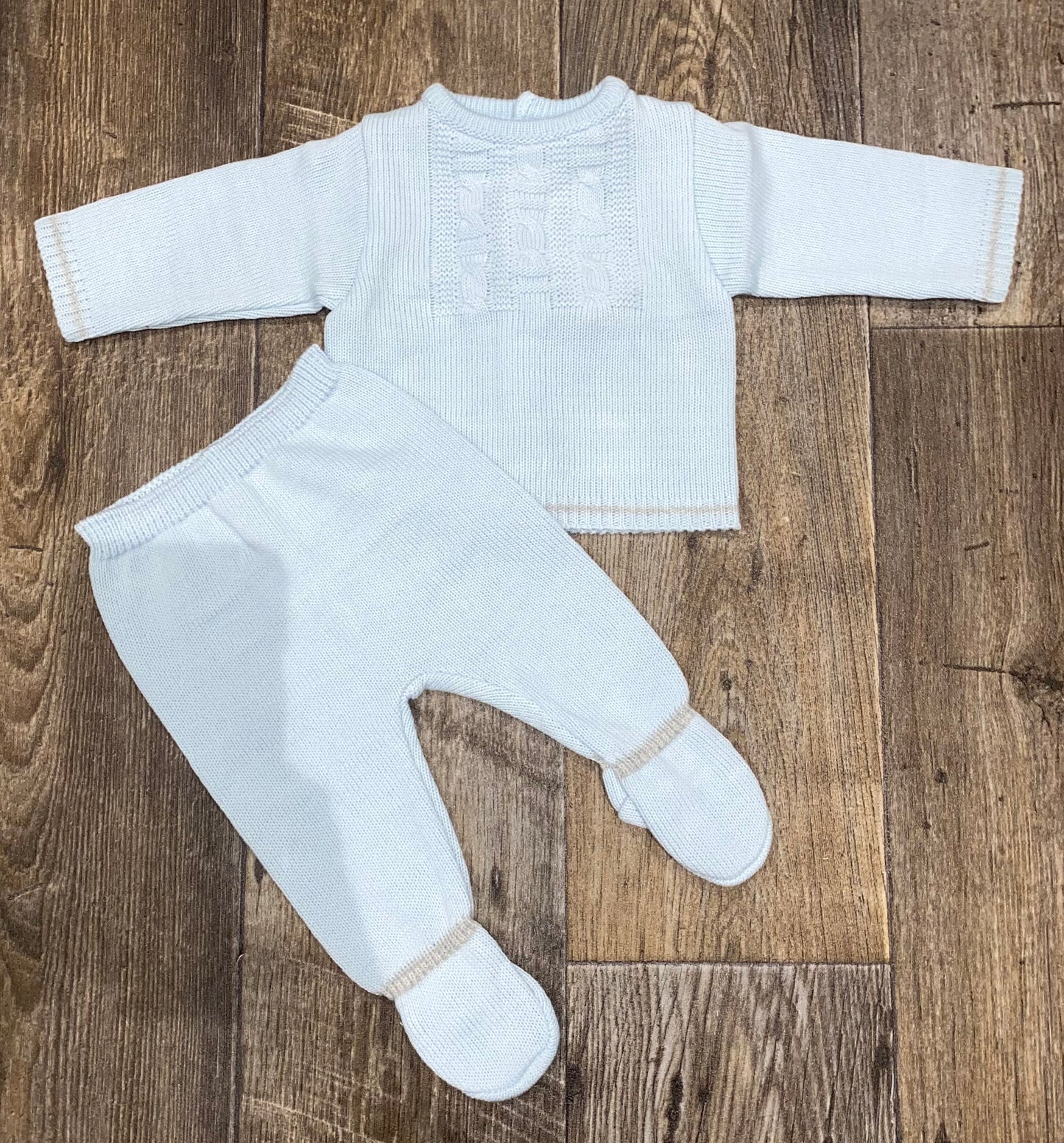 blue knitted baby outfit with long-sleeve top and pants on a wooden floor
