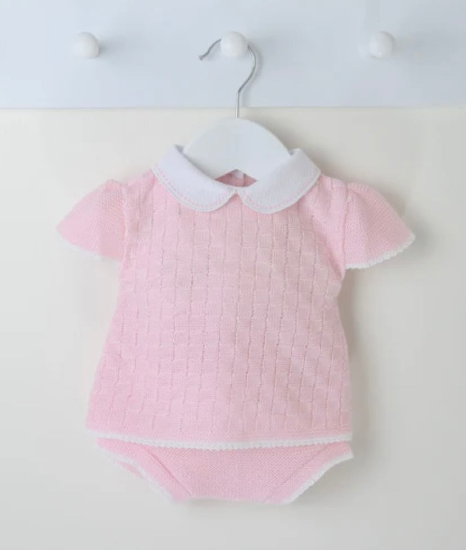 Pink baby outfit with white collar on a hanger against a white background