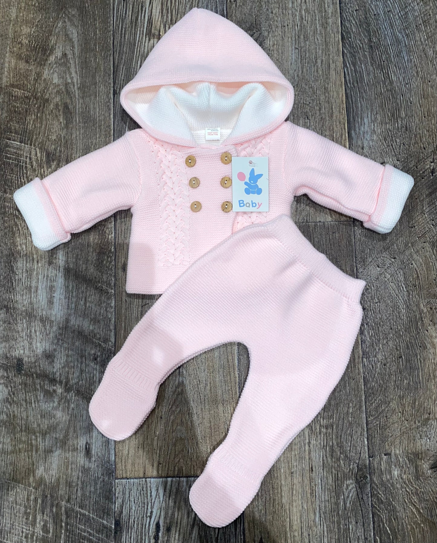 Pink baby outfit with a hood on a wooden surface