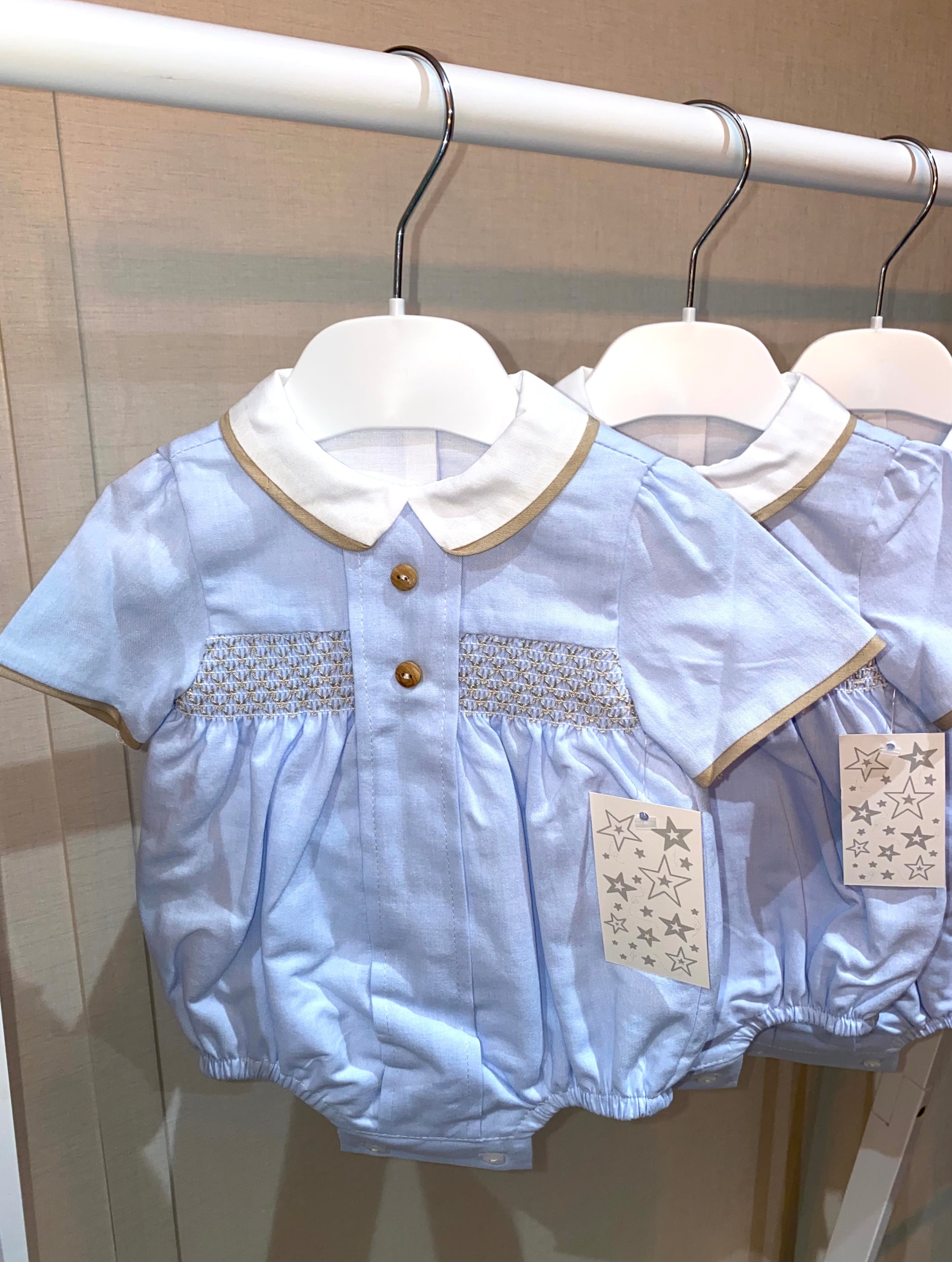 Light blue baby romper with white collar and tan smocking and trim