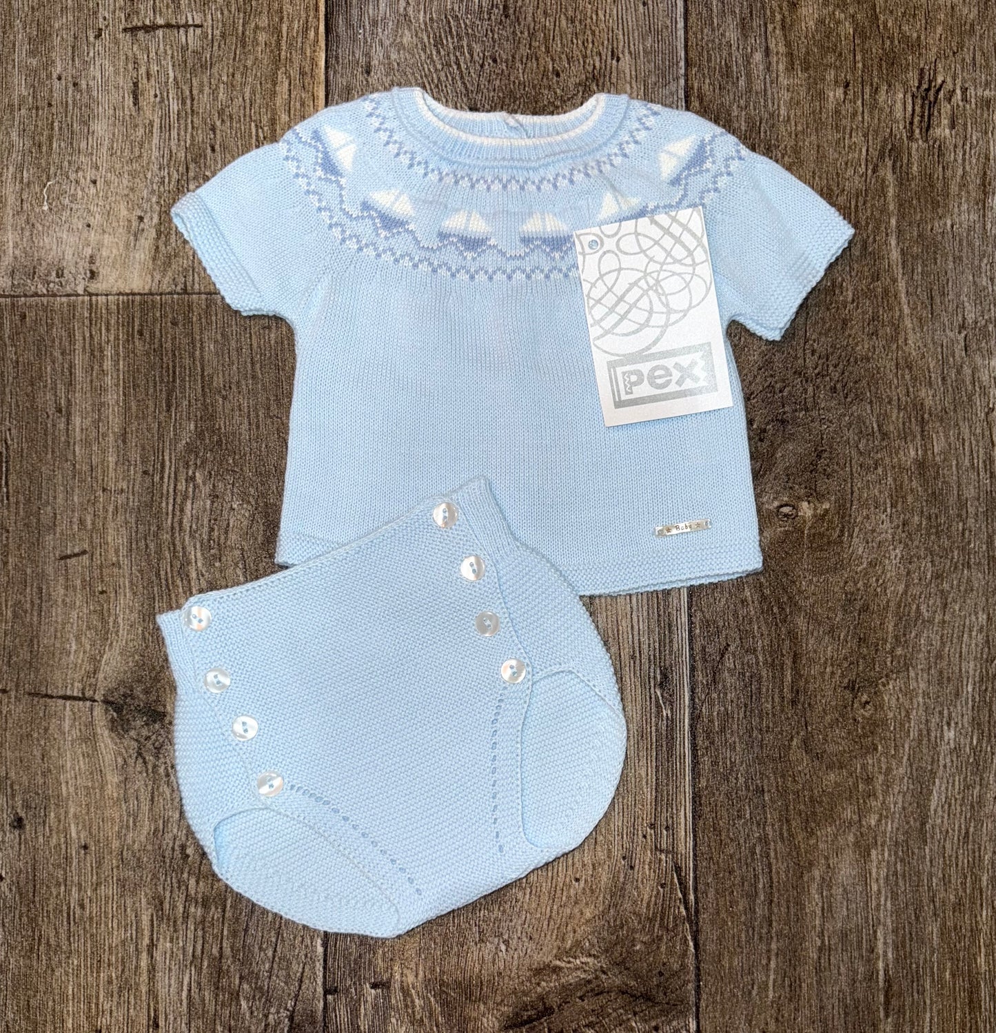Light blue baby outfit with matching jam pants on a wooden surface
