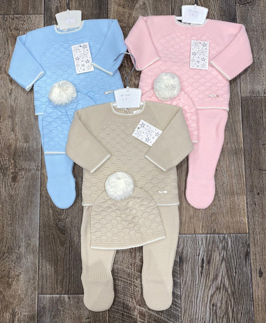 Three baby outfits in blue, beige, and pink on a wooden floor.