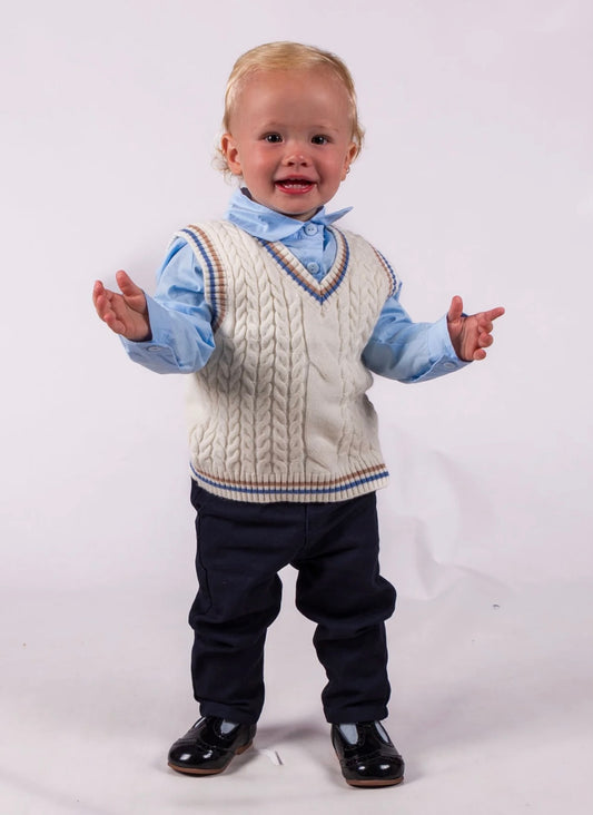 Baby wearing a cable knit vest over a shirt with rolled-up sleeves, black pants, and shiny shoes on a white background.