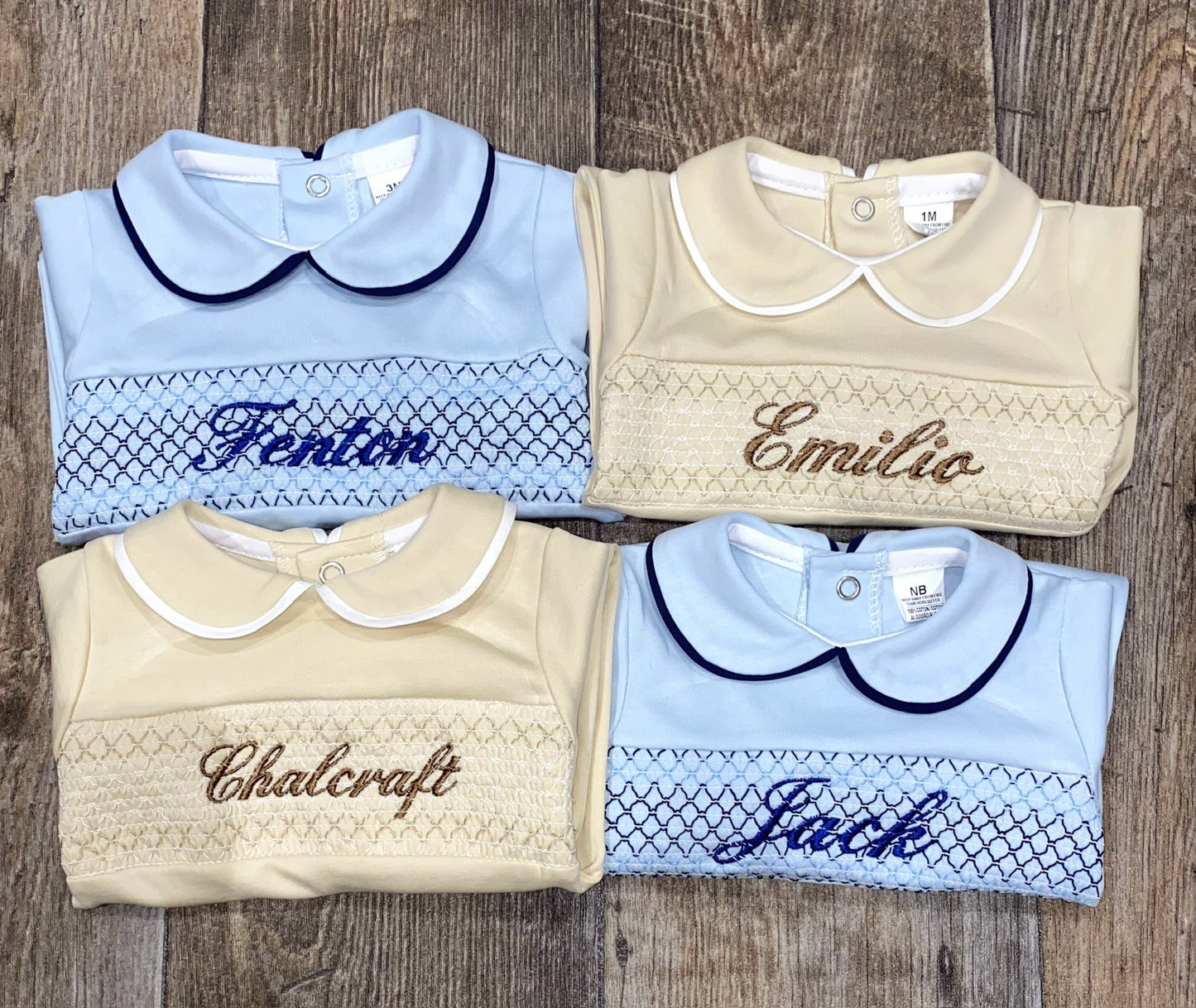 Four children's all in ones with embroidered names on a wooden surface