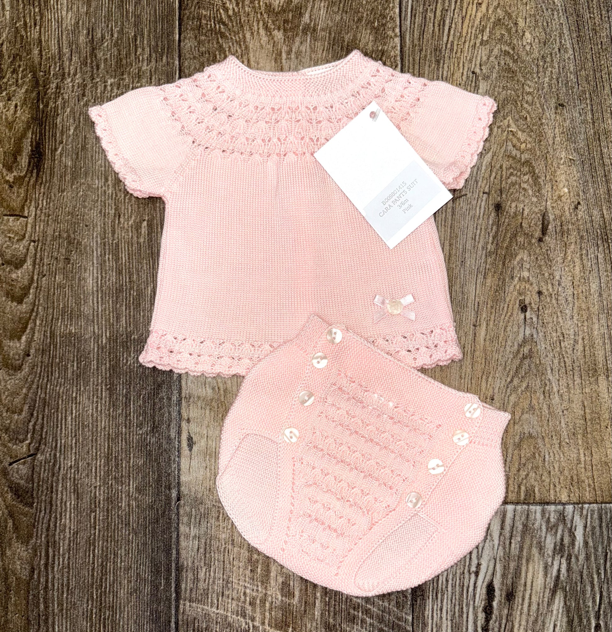 Pink baby outfit with matching knickers on a wooden surface
