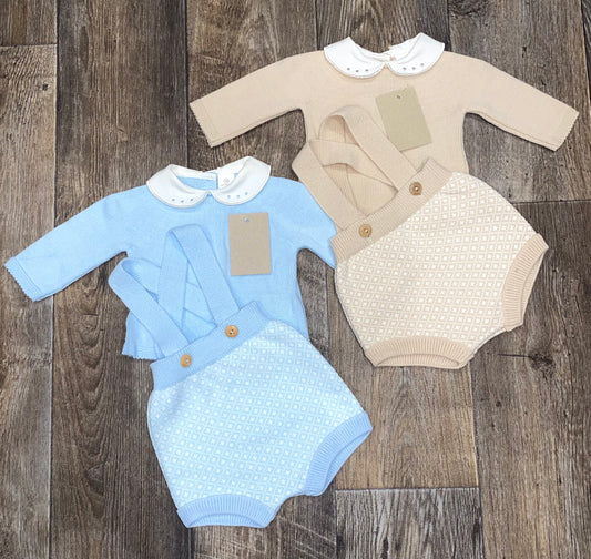 Two knitted spanish style baby outfits, one blue and one beige, on a wooden surface.