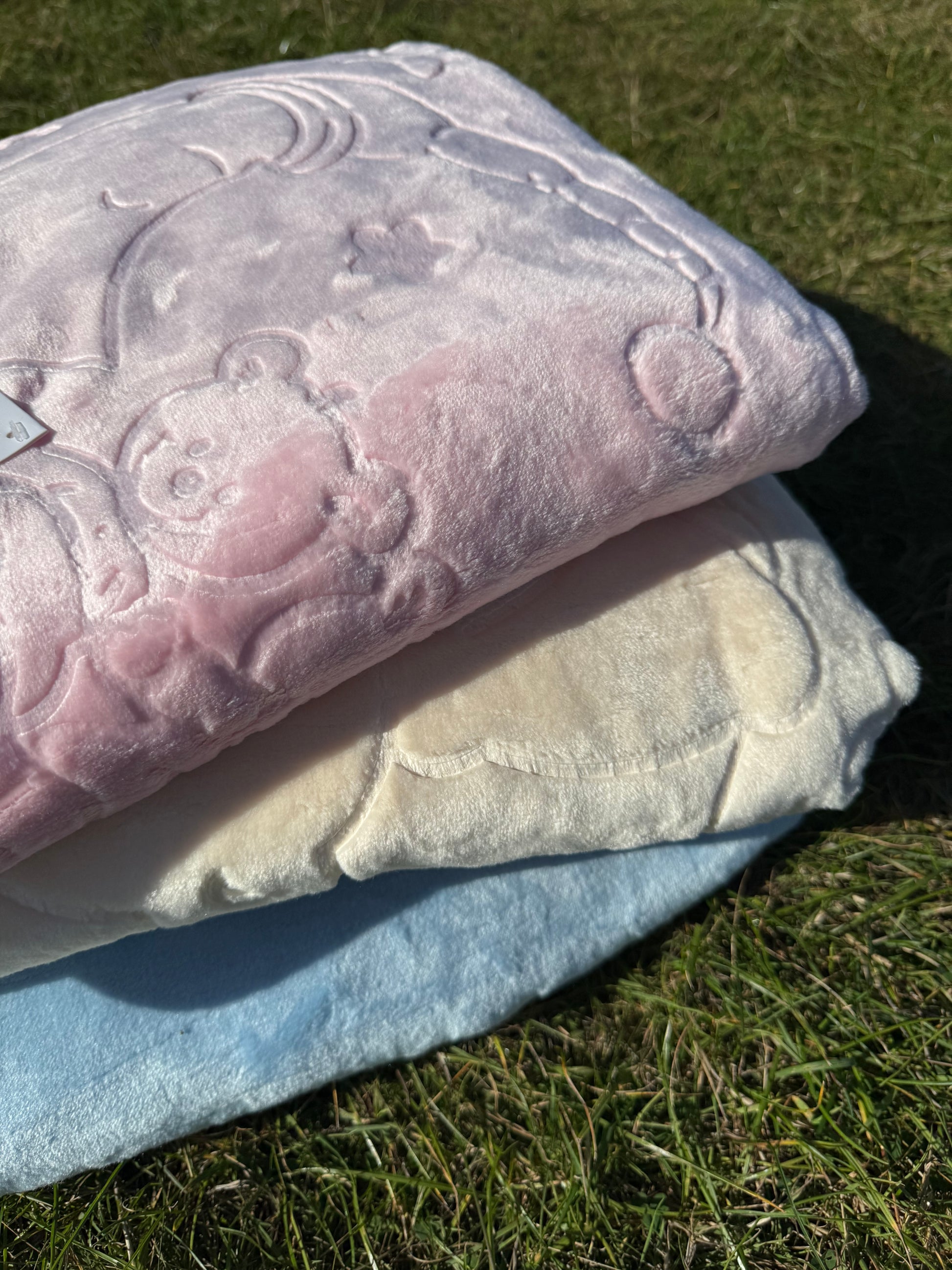 Folded pink and blue baby blankets showing embossed detailing