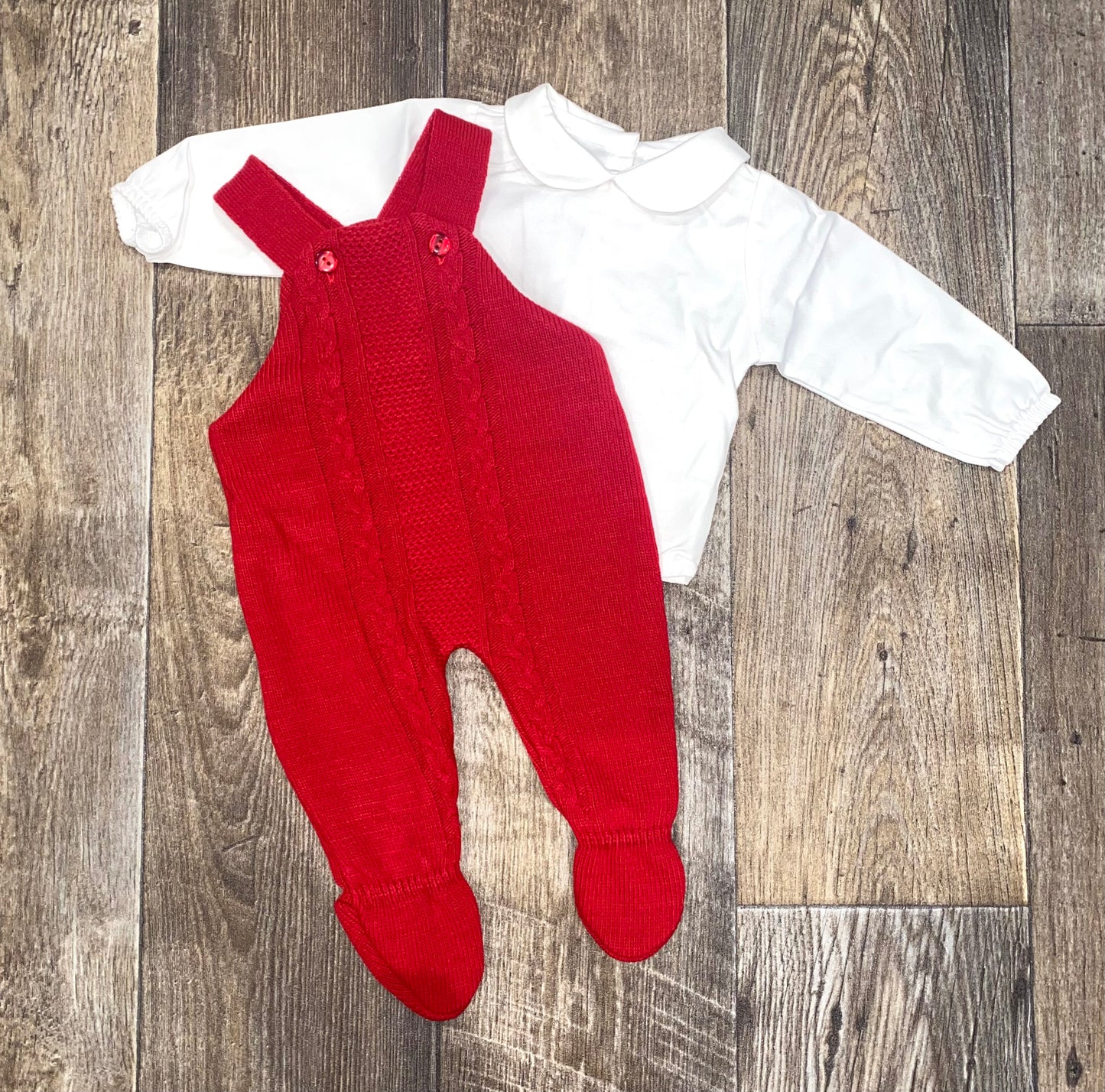 Red knitted baby romper with white shirt on wooden floor