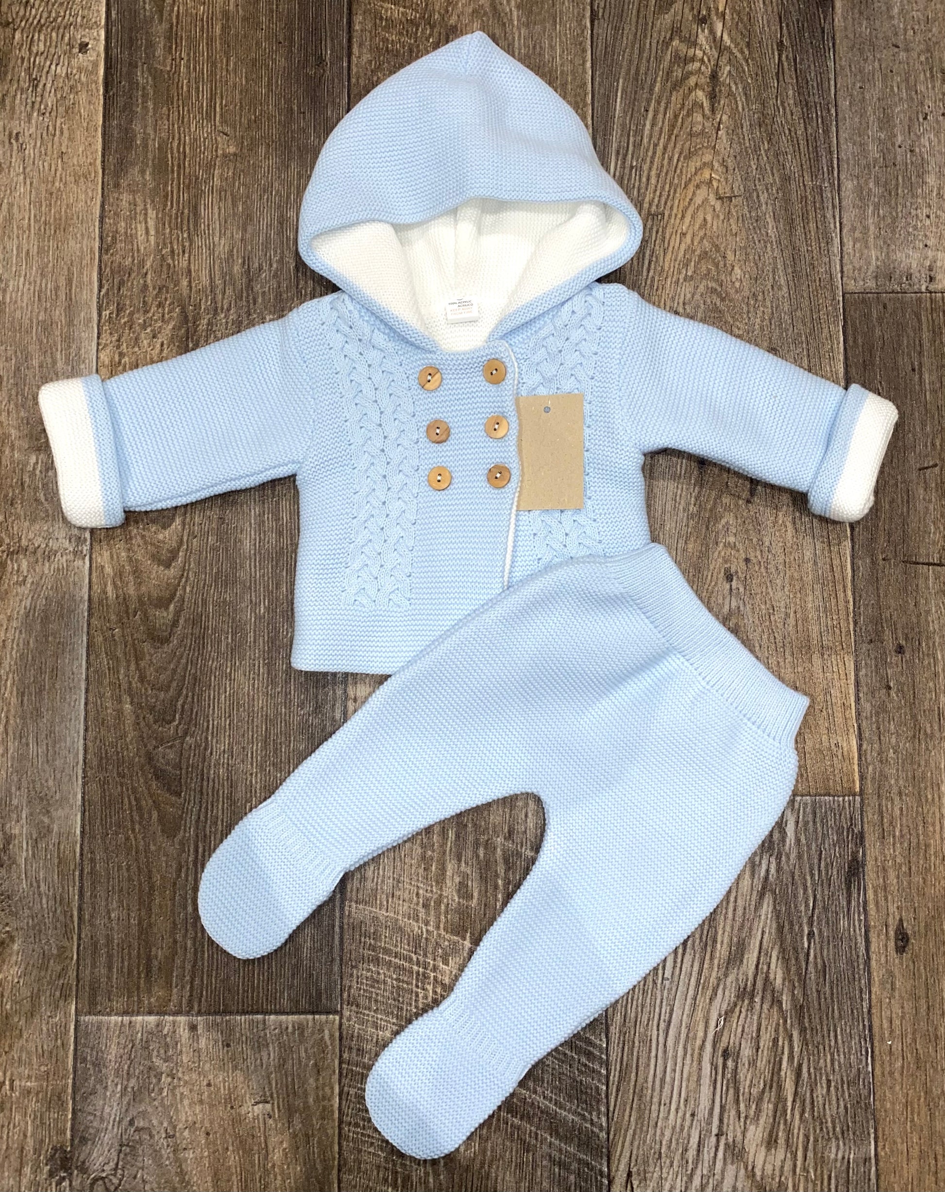 Baby outfit with a blue knitted jacket and pants on a wooden floor