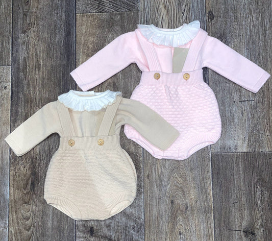 Two baby rompers, one pink and one beige, on a wooden surface.