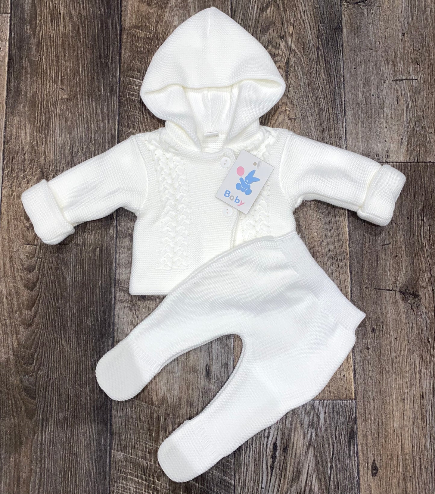 White baby outfit with a hood on a wooden surface