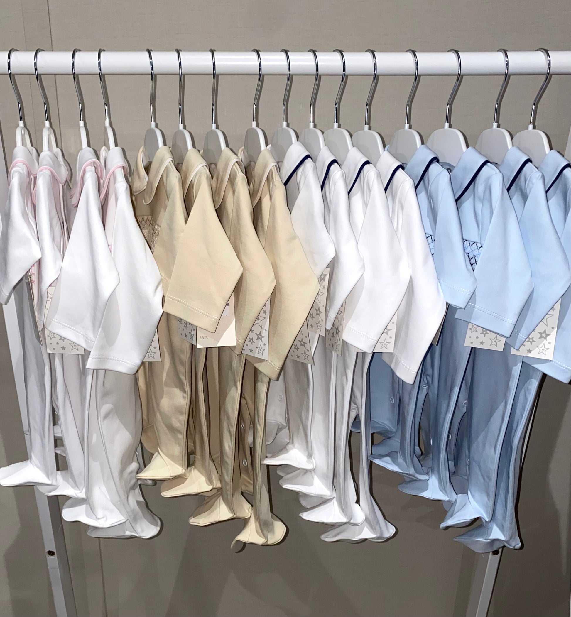 Row of baby sleepsuits on hangers against a neutral background